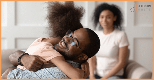 Black father embracing daughter, mom in the background