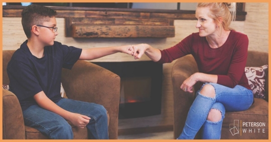 Adult woman bumping fists with teenage boy