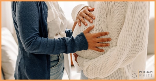 Woman putting hands on a pregnant woman's stomach