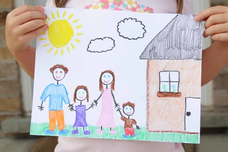 Little girl holding up drawing of a family