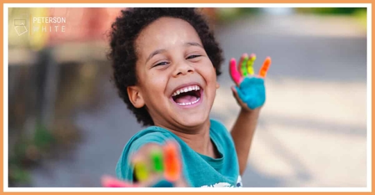 Kid playing with finger paint, smiling and laughing
